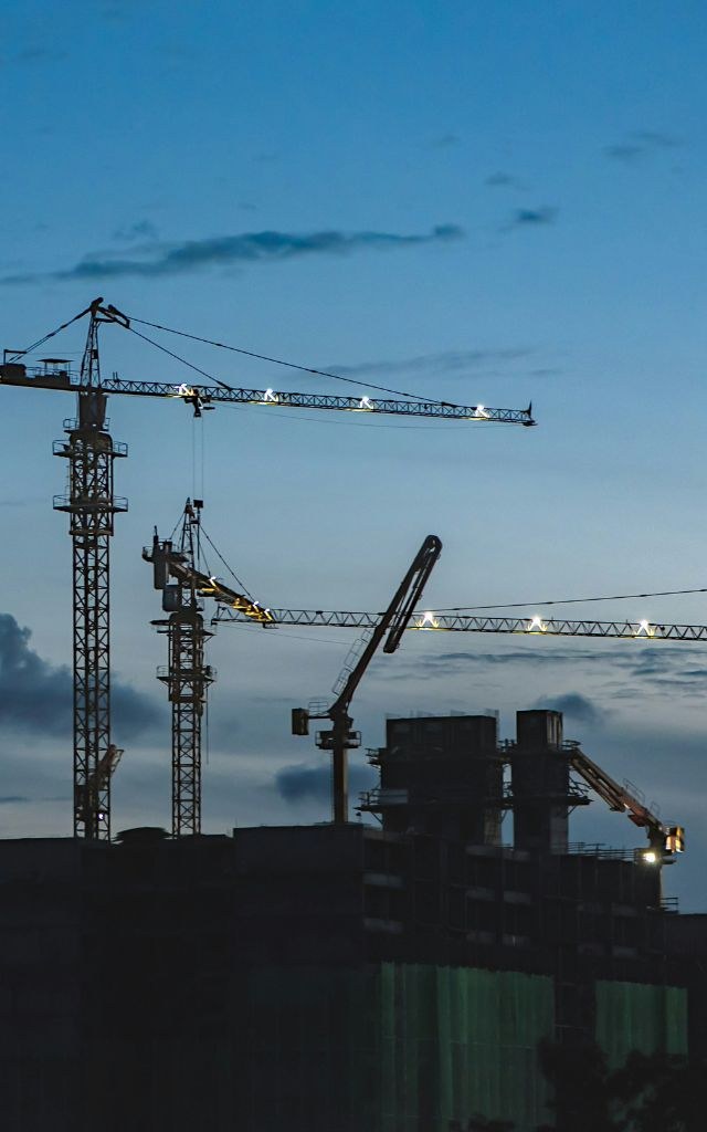 Tower cranes over a commercial construction site at dusk