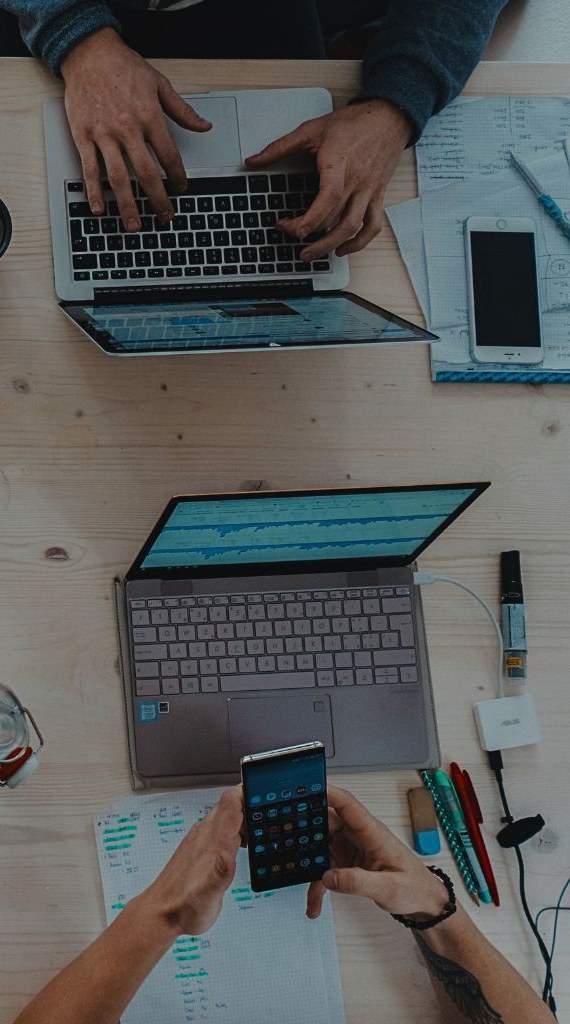 Two people working across laptops and notes at a shared desk